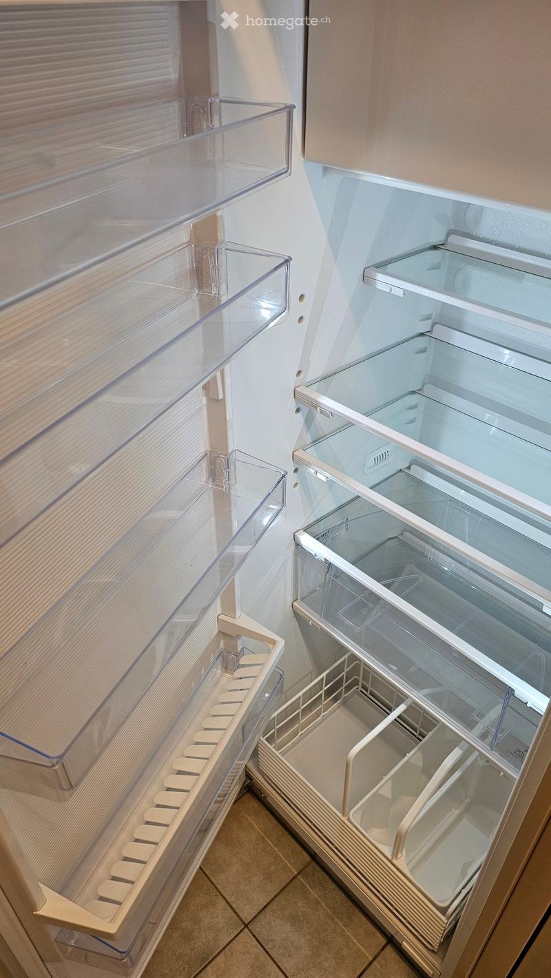 An empty refrigerator with clear drawers and shelves