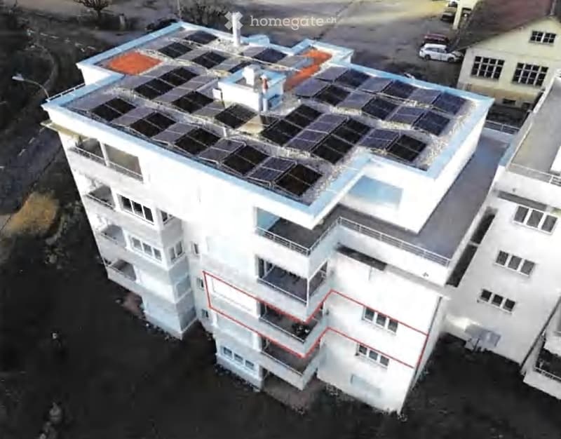 A multi-story building with solar panels on the roof, multiple balconies, and a modern design.