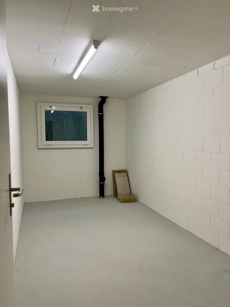 Empty room with white brick walls, a window, a door, and a small cardboard box on the floor.
