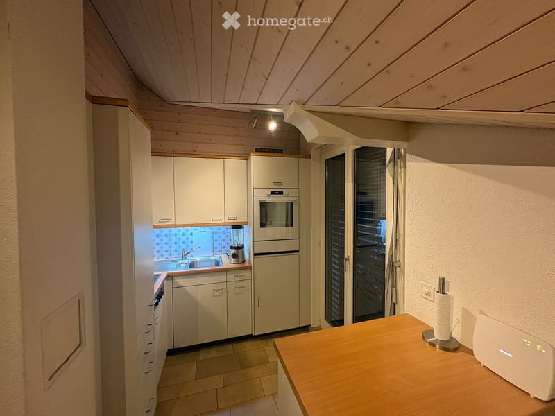 Modern kitchen with light wood cabinets, stainless steel appliances, and a wooden countertop. Features include a sink, faucet, oven, refrigerator, and a blender on the counter.
