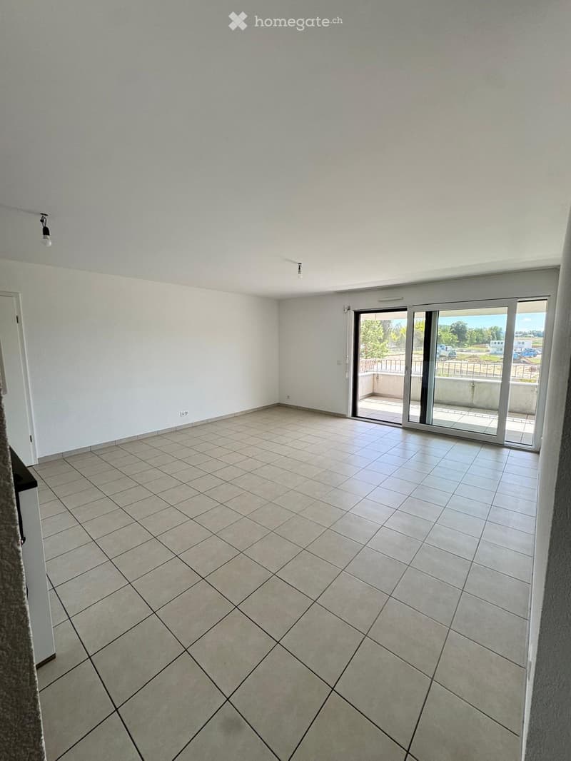 Empty room with tiled floor, white walls, and large sliding glass doors leading to a balcony.