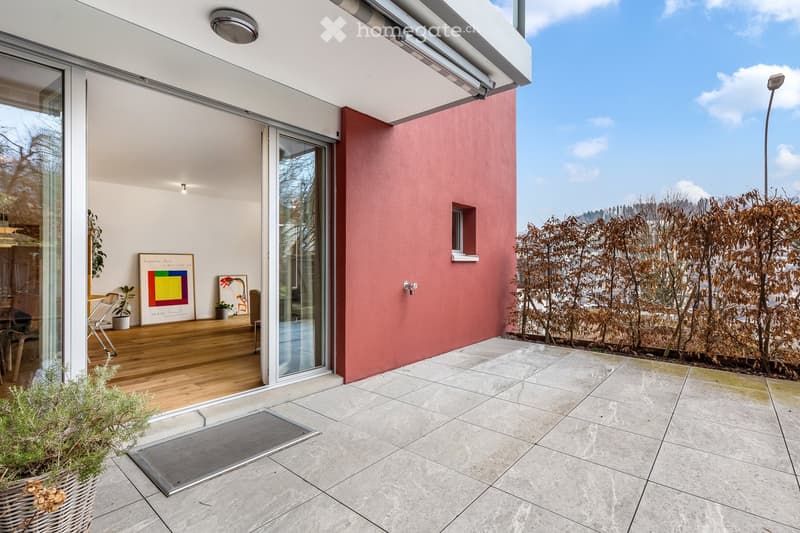 large outdoor patio, terrace with sliding glass door, concrete floor, wall covered in shrubs, view of hills in the distance