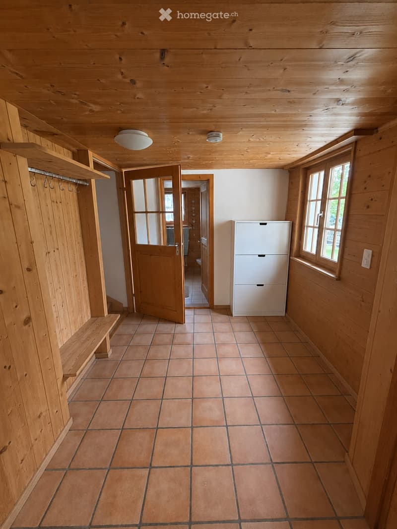 Empty hallway with wooden walls, tiled floor, built-in bench, and open doors leading to other rooms.