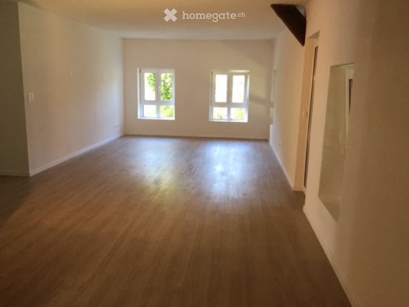 Empty room with wooden flooring and two windows, no furniture or equipment.