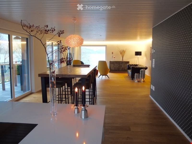 Open-plan living and dining area with modern furniture, large windows offering a view, and warm lighting.