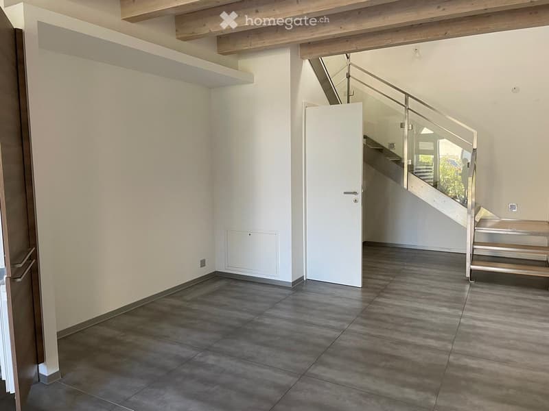 Empty hallway with tiled floor, white walls, and a staircase leading upwards with a glass railing.