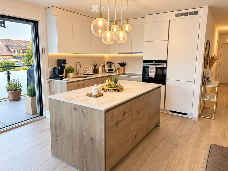 Modern kitchen with white cabinets, wooden island, marble countertop, pendant lights, and a view of the balcony.
