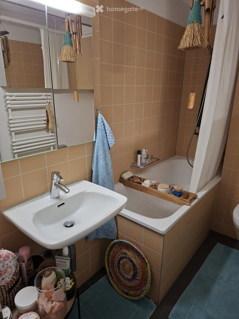 Bathroom with a white sink, bathtub, mirror, radiator, and various bathroom accessories neatly arranged on a wooden tray and shelf.