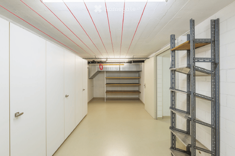 Empty storage room with white walls, wooden shelving, and metal shelving units. No furniture or equipment present.