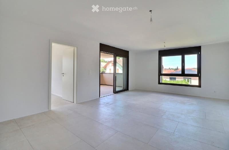 Empty room with white walls, tiled floor, large window, and sliding glass door leading to a balcony.
