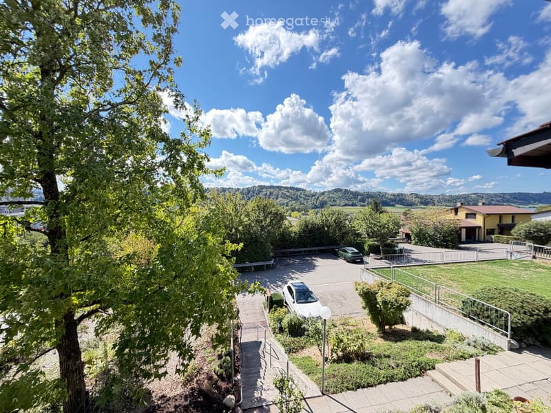 Balcony view showing a landscaped garden area with a parking lot, stairs, and a scenic valley view.