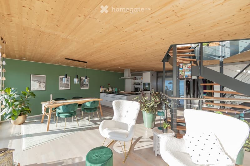 Open-concept living and dining area with modern furniture, pendant lights, and a staircase leading to an upper level.