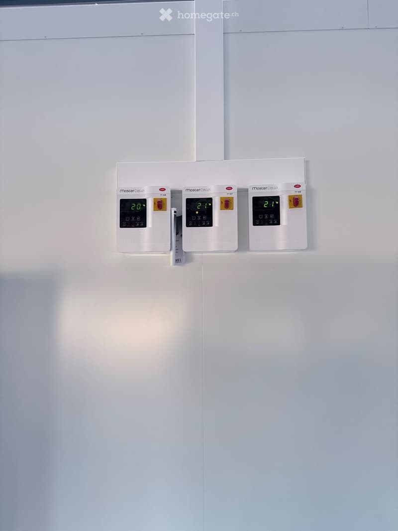 Three white thermostats mounted on a wall, displaying temperatures of 20°C, 21°C, and 21°C respectively.