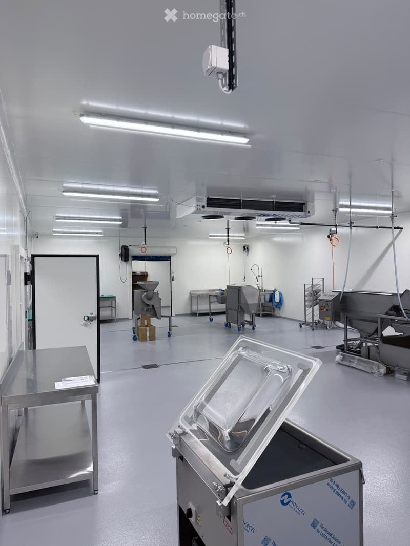 Clean, modern industrial room with stainless steel equipment, tables, and a large open space.