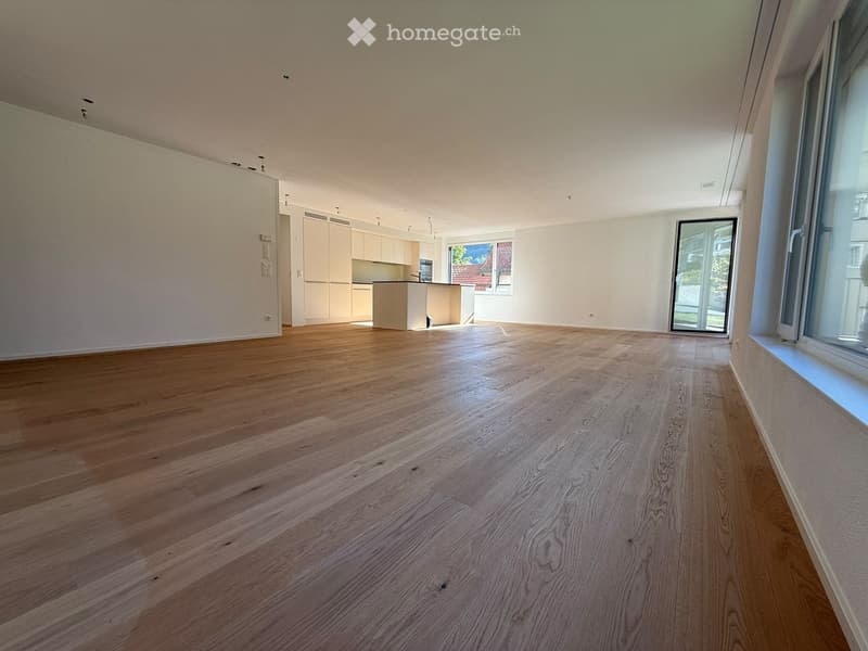 Empty room with wooden flooring, white walls, and large windows. No furniture or equipment present.