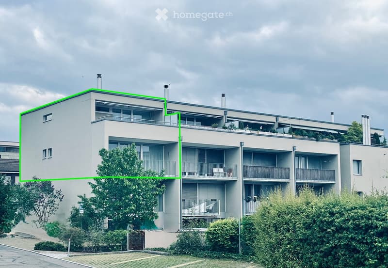 Modern multi-story residential building with balconies, large windows, and surrounding greenery.