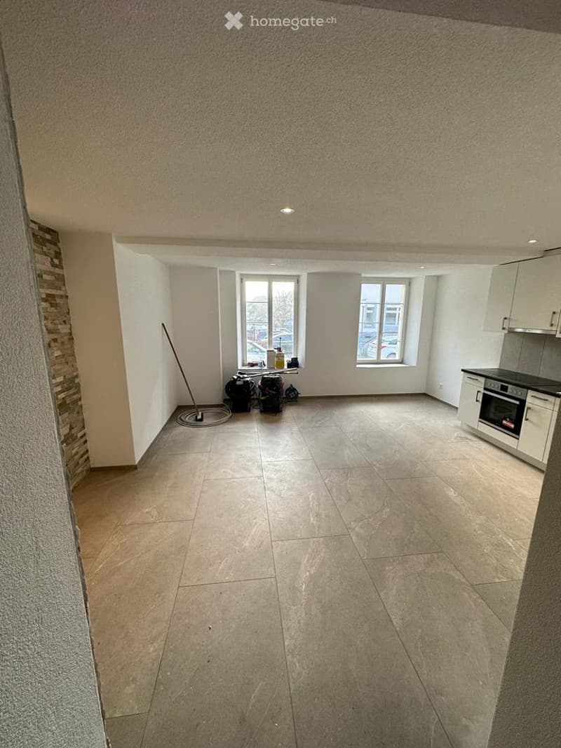 Empty room with tiled floor, white walls, and large windows. No furniture or equipment present.