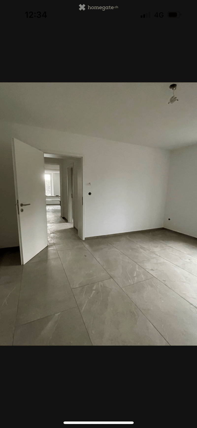 Empty room with tiled floor and white walls, featuring an open doorway leading to another room.
