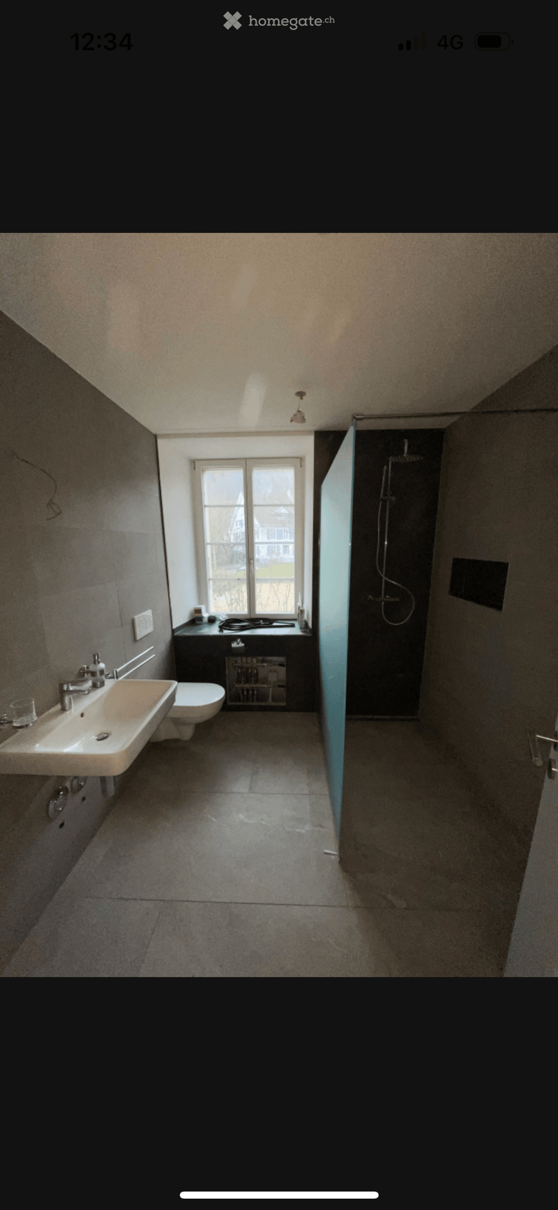 Modern bathroom with a large window, sink, toilet, and separate shower area with glass enclosure.