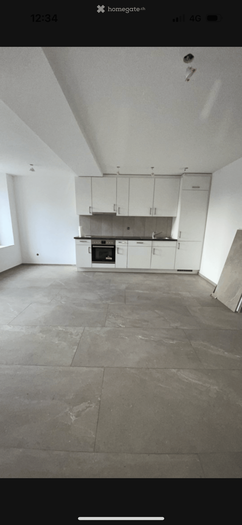 Empty kitchen with white cabinets, stainless steel appliances, and a large concrete floor. No furniture or items present.