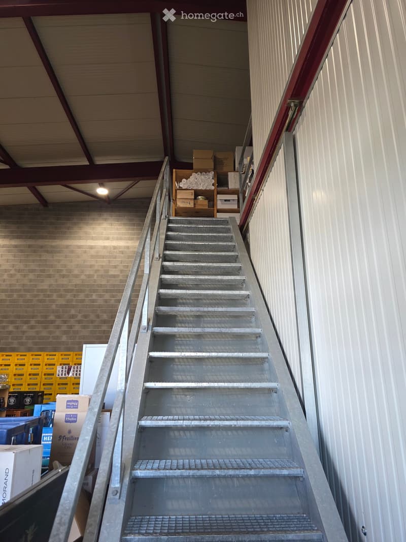Metal staircase leading upwards with a railing, surrounded by storage boxes and crates on both sides.