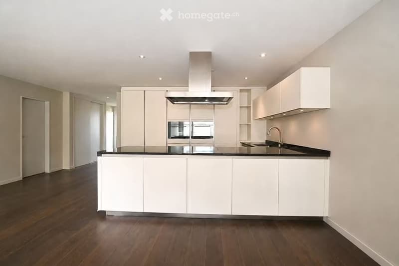 Modern kitchen with white cabinetry, black countertops, a central island, and built-in appliances including a range hood and oven.
