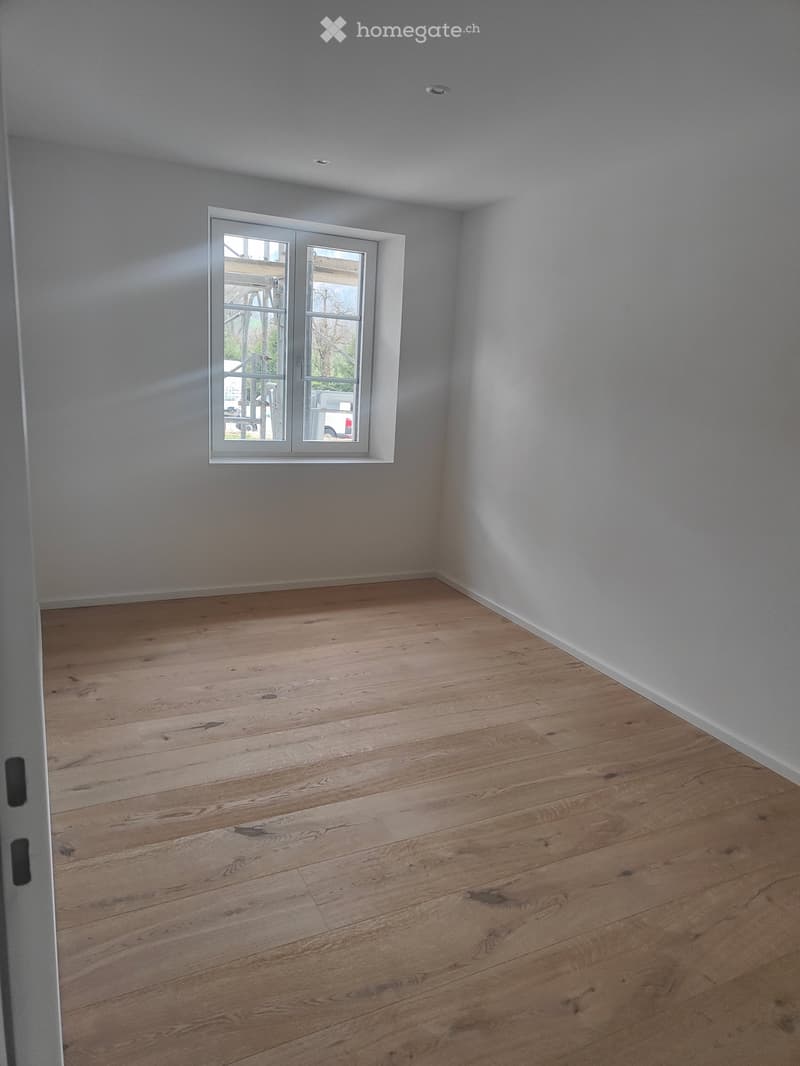 Empty room, hardwood floors, white walls, large window, hallway