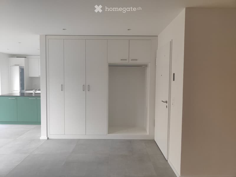 Empty room with white wardrobe, green kitchen cupboards, grey tiled floor, sink with faucet