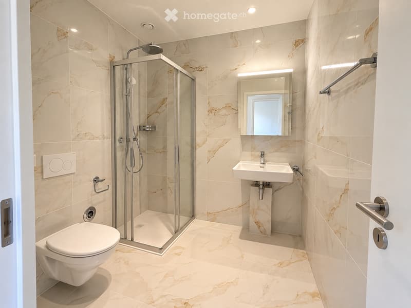 Modern bathroom with marble tiles, a glass-enclosed shower, a toilet, a sink with a mirror, and built-in lighting.