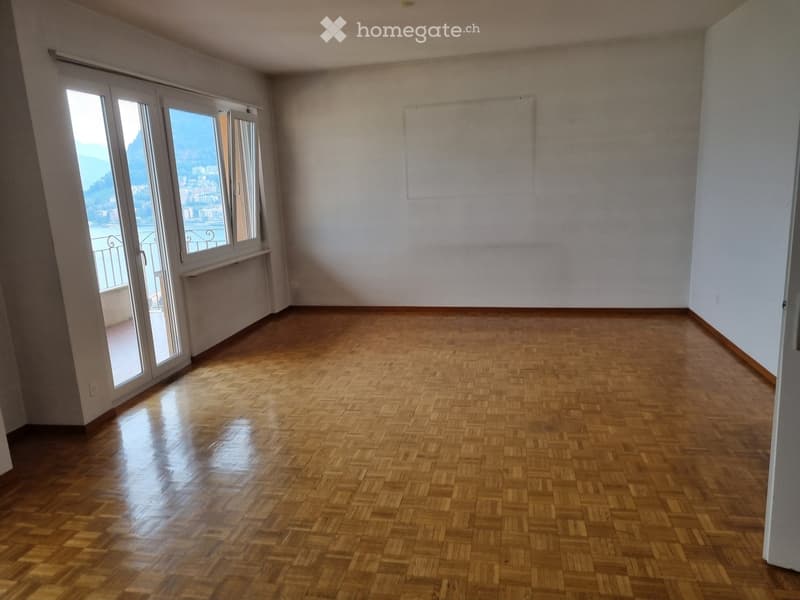 Empty room with wooden flooring, large windows offering a scenic view, and white walls.