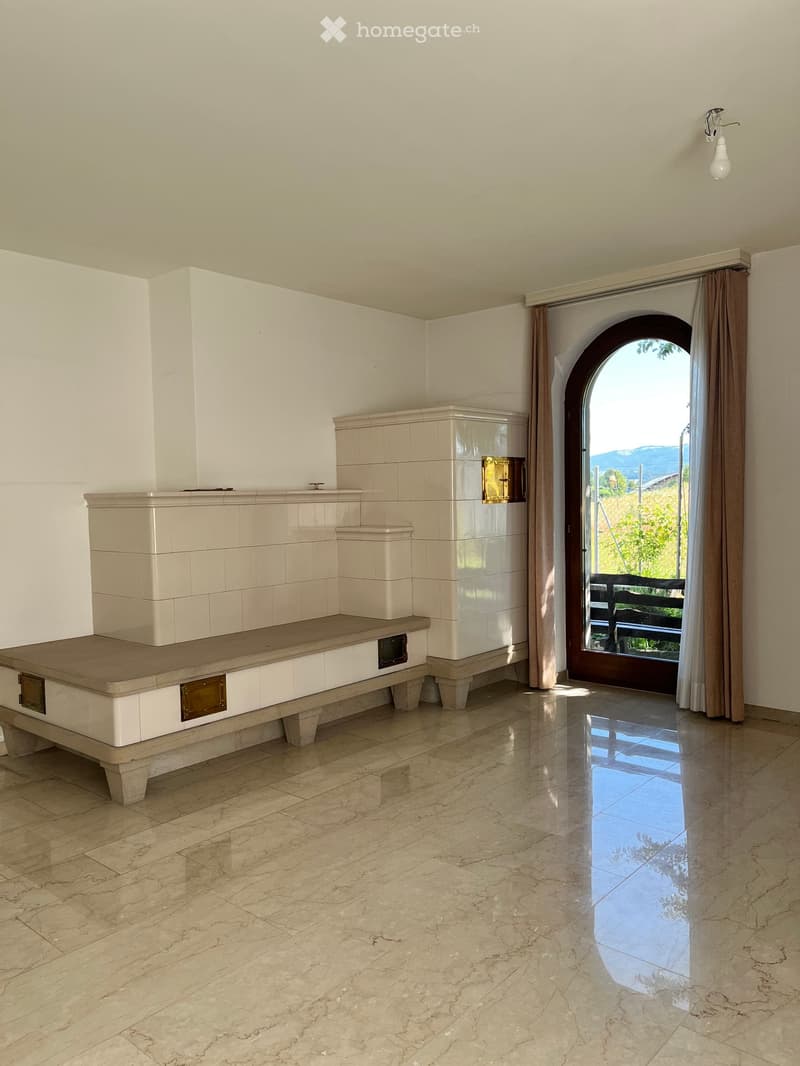 Empty room with marble flooring, white tiled walls, built-in bench seating, and an arched doorway leading to an outdoor area.