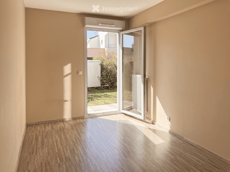 Empty room with wooden flooring, light-colored walls, and large sliding glass doors leading to an outdoor area.