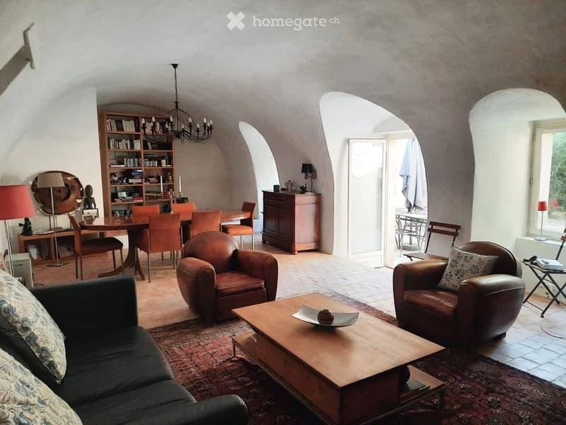vaulted ceilings, dark leather armchairs, wooden coffee table, bookshelf, dining table and chairs, carpet, lamps