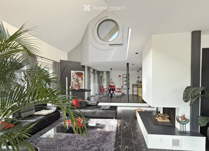 Modern living room with a black leather sofa, glass coffee table, fireplace, and a dining area with red chairs and a black table.