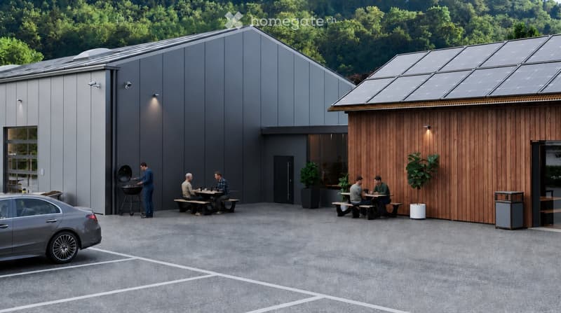 Modern building with grey and wooden facades, solar panels on the roof, outdoor seating area with picnic tables, and a barbecue area.
