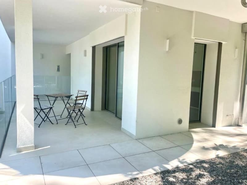 Balcony with tiled floor, white walls, and a small table with four chairs near the glass door entrance.