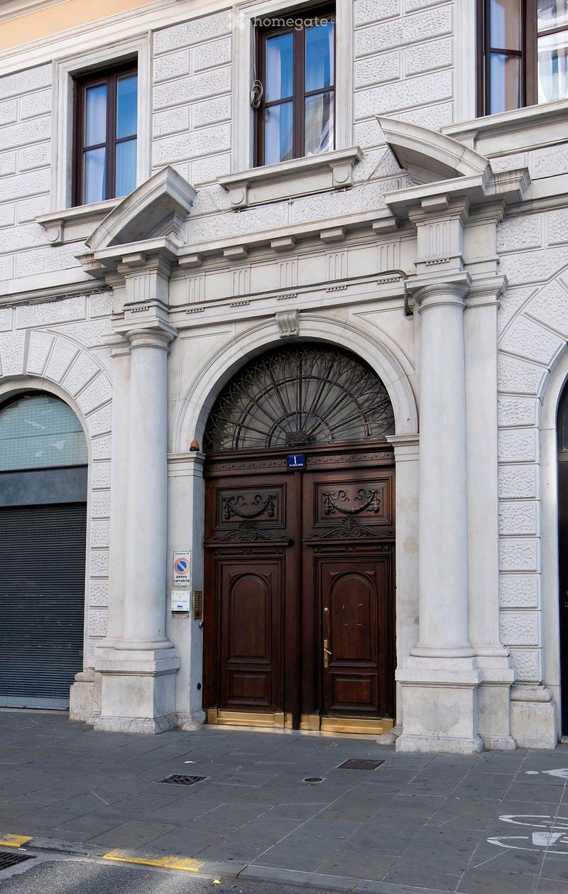 Ornate building entrance with large double doors, decorative columns, and arched windows.