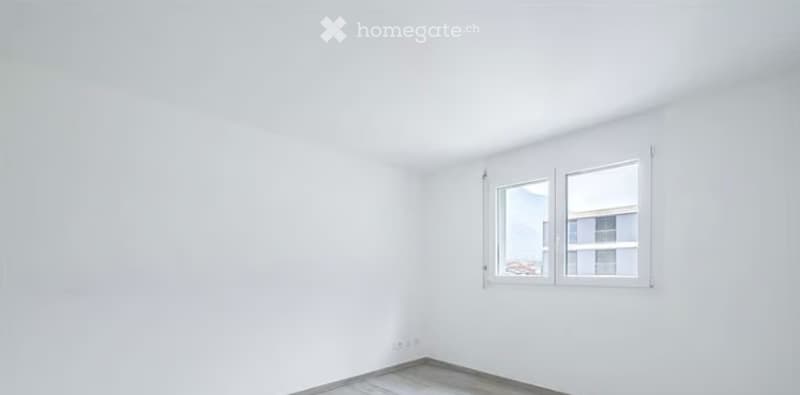 Completely empty room with white walls, grey tiled floor, and a single window with white frame and glass panels.