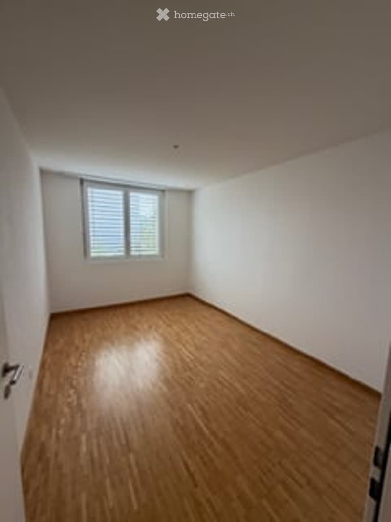 Empty room with wooden flooring, white walls, and a single window with blinds. No furniture or equipment present.