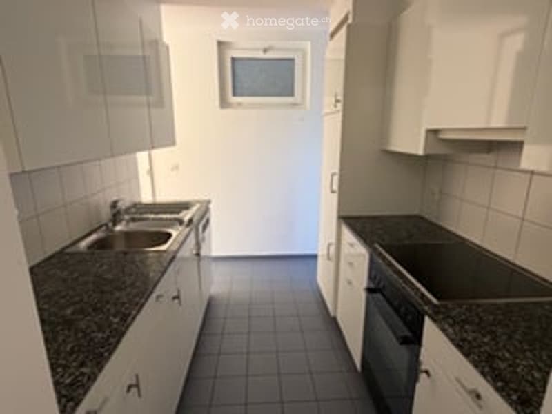 Modern kitchen with white cabinets, granite countertops, and stainless steel appliances including a sink, stove, and oven.
