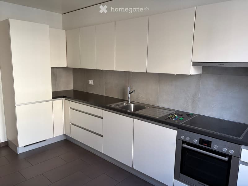Modern kitchen with white cabinets, black countertop, stainless steel sink, and Bosch oven.