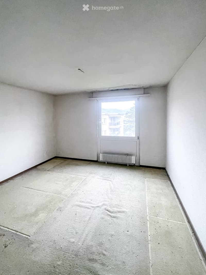 Empty room with white walls, tiled floor, and a single window with a radiator below it.