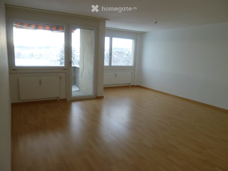Empty room with wooden flooring, white walls, large windows, and radiators. No furniture or equipment present.