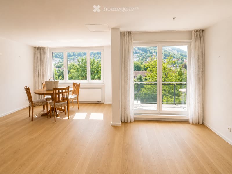 Bright dining area with wooden floor, large windows offering scenic views, dining table with chairs, and a handbag on the table.