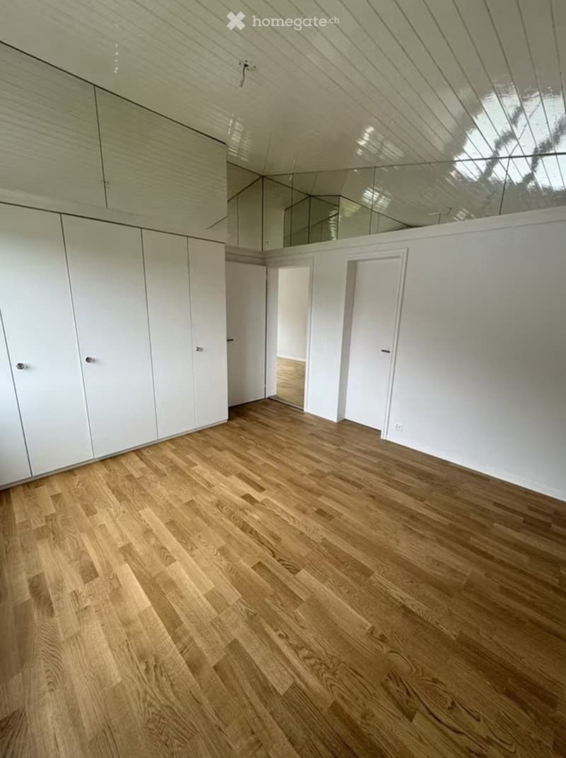 Completely empty room with light wooden flooring, white walls, and built-in white cabinets. No furniture or equipment present.