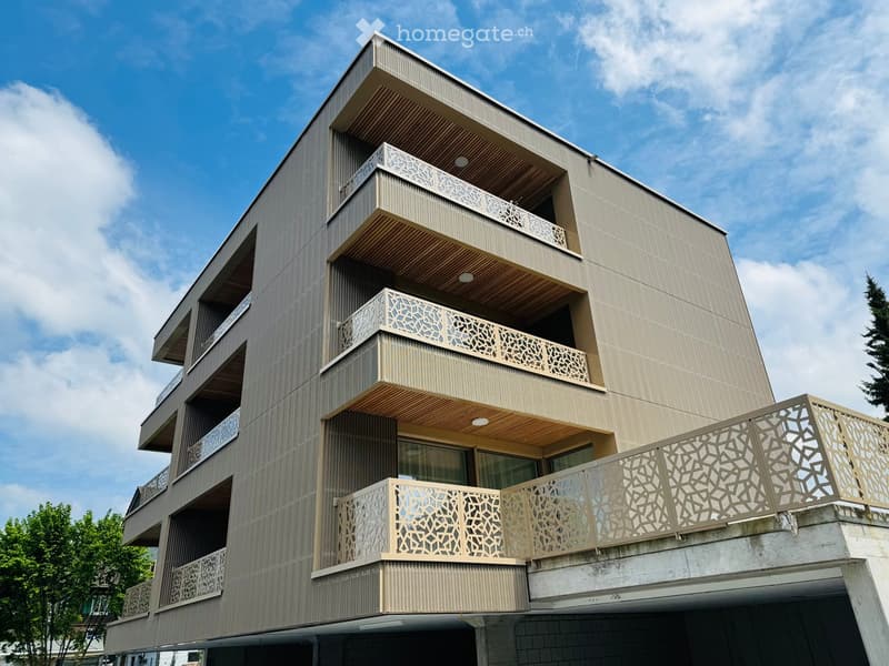Modern multi-story building with balconies and decorative railings, featuring a sleek, contemporary design.