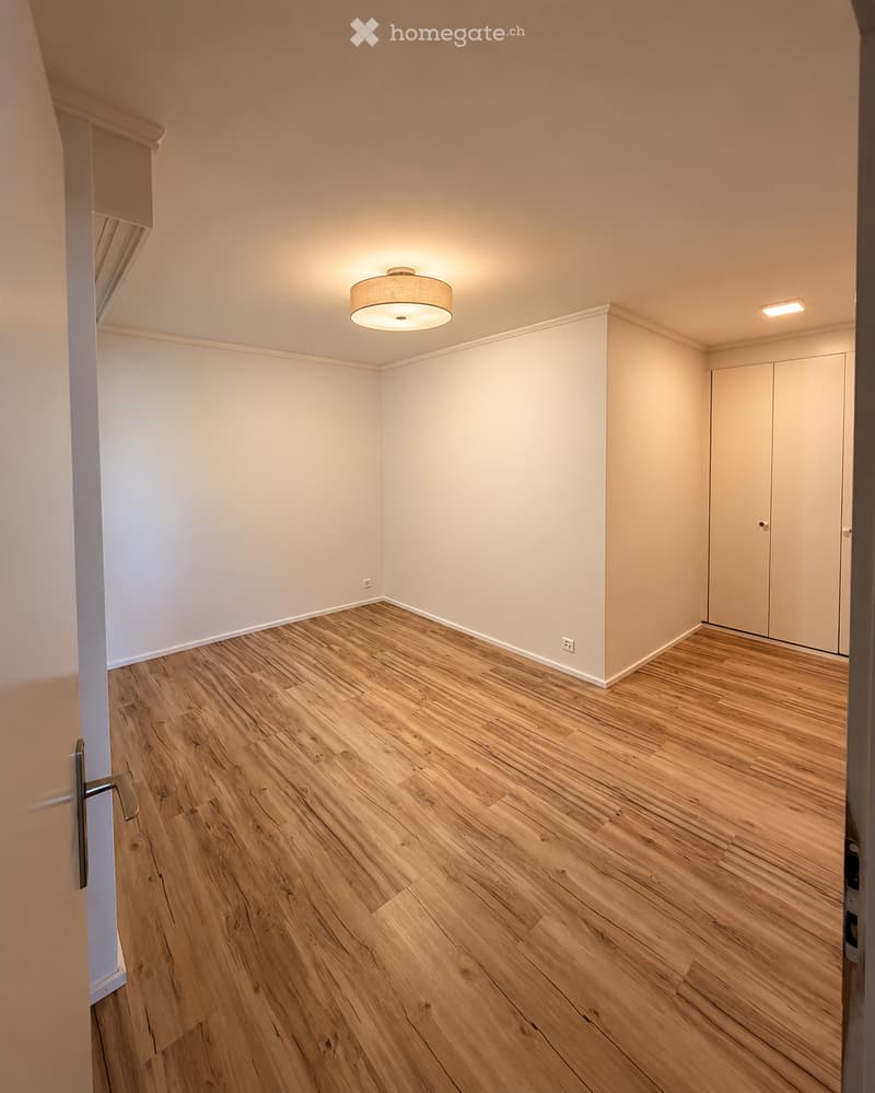 Empty room with light wooden flooring, white walls, and a single ceiling light fixture. No furniture or personal items are present.