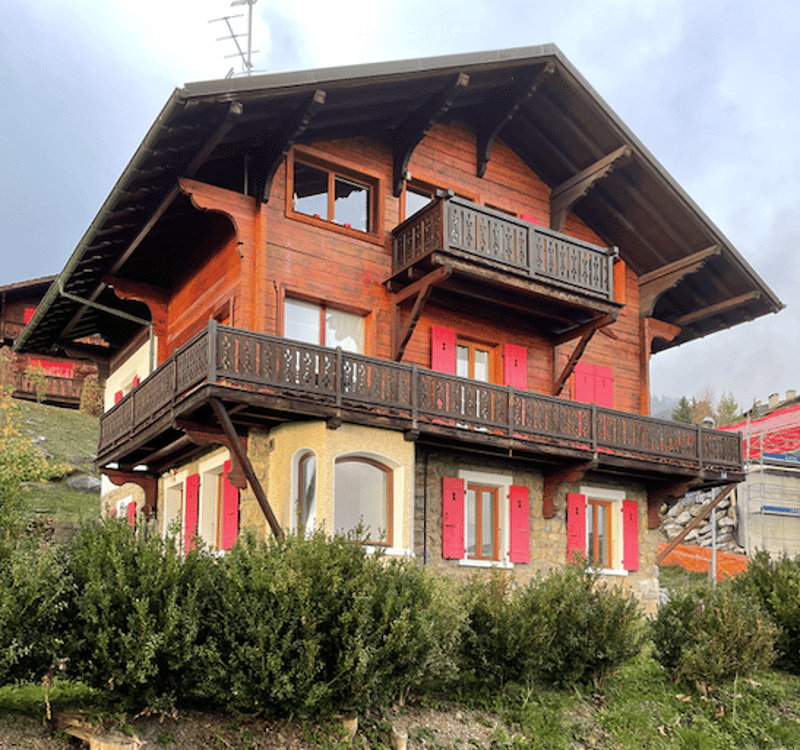 2-story wooden chalet-style house with red exterior, large balconies, and wooden beams