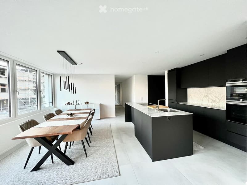 Modern kitchen and dining area with a wooden dining table, chairs, a central island with sink and faucet, and built-in black cabinets.