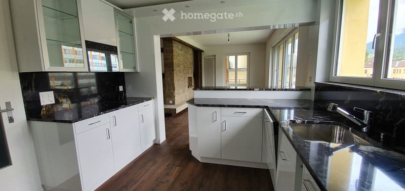 Modern kitchen with white cabinets, black countertops, and a stainless steel sink.